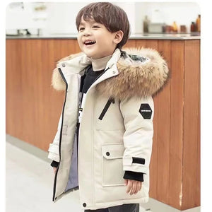 Child wearing a white winter coat with a fur-lined hood in an indoor setting.