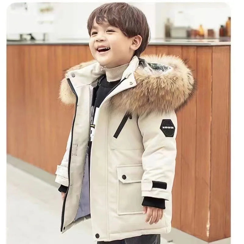 Child wearing a white winter coat with a fur-lined hood in an indoor setting.