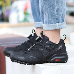 Black outdoor shoes worn with rolled-up jeans on a blurred background