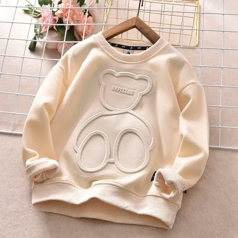 Beige sweatshirt with bear design on a hanger against a grid background