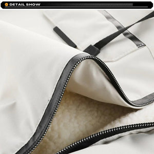 Close-up of a white jacket with black zipper and trim on a light gray background.