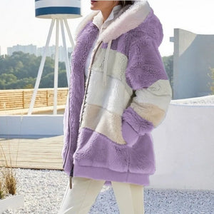 Person wearing a purple and white sherpa jacket outdoors with a blurred background