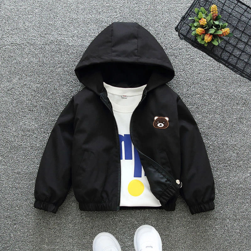 Black hooded jacket with a bear patch on a gray surface