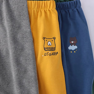 Three pairs of pants in gray, yellow, and blue with bear illustrations on a white background.