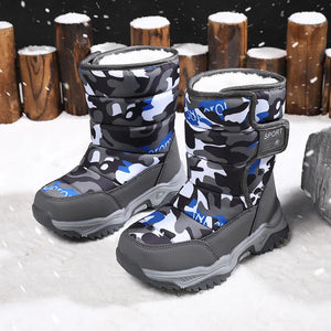 Camouflage-patterned snow boots with gray soles on a snowy background