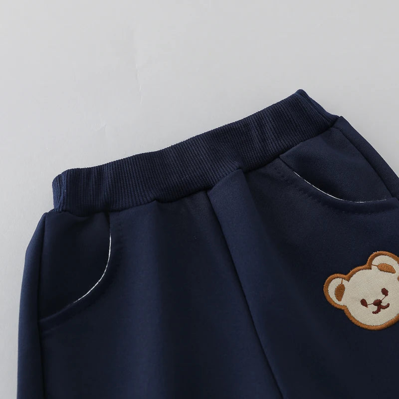 Navy blue pants with a teddy bear patch on a light gray background