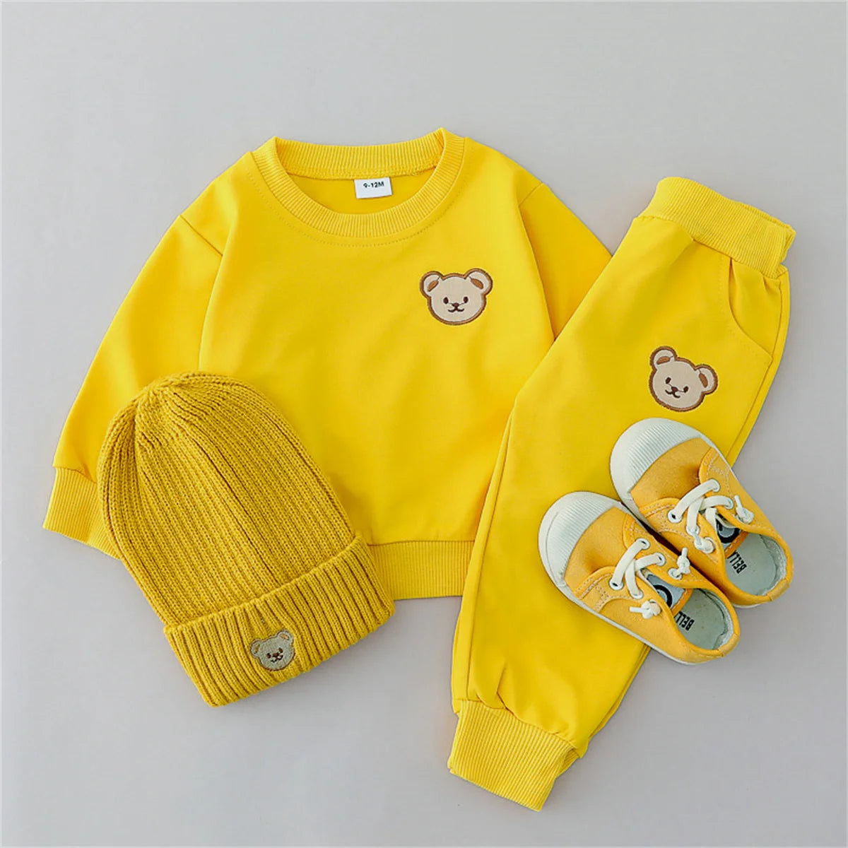 Yellow children's outfit with bear face design on a gray background