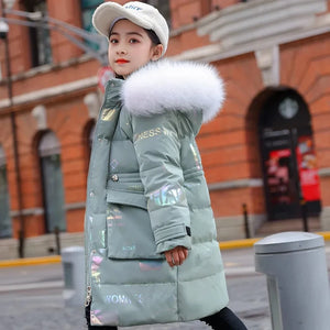 Person wearing a long green puffer coat with a fur-lined hood on a city street.