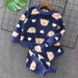 Children's navy blue pajama set with teddy bear and heart patterns on a gray surface.