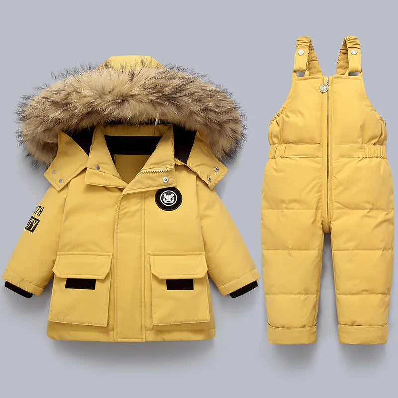 Yellow winter coat with fur hood and matching snow pants on a gray background