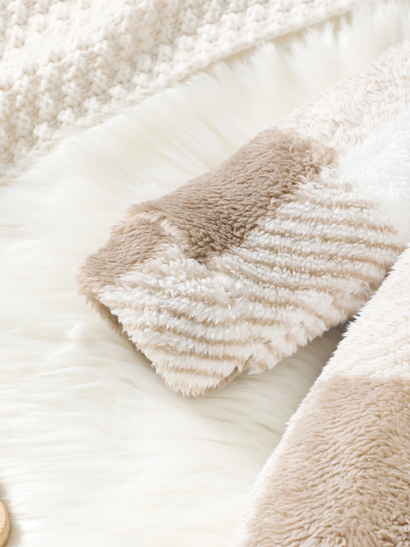 Close-up of a fluffy beige blanket with a textured pattern on a soft white background