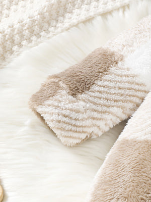 Close-up of a fluffy beige blanket with a textured pattern on a soft white background