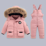 Pink winter coat with fur hood and matching snowsuit on a gray background