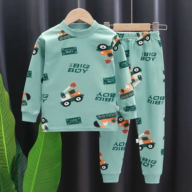 Children's pajama set with 'Big Boy' and truck prints on a hanger against a dark curtain background.