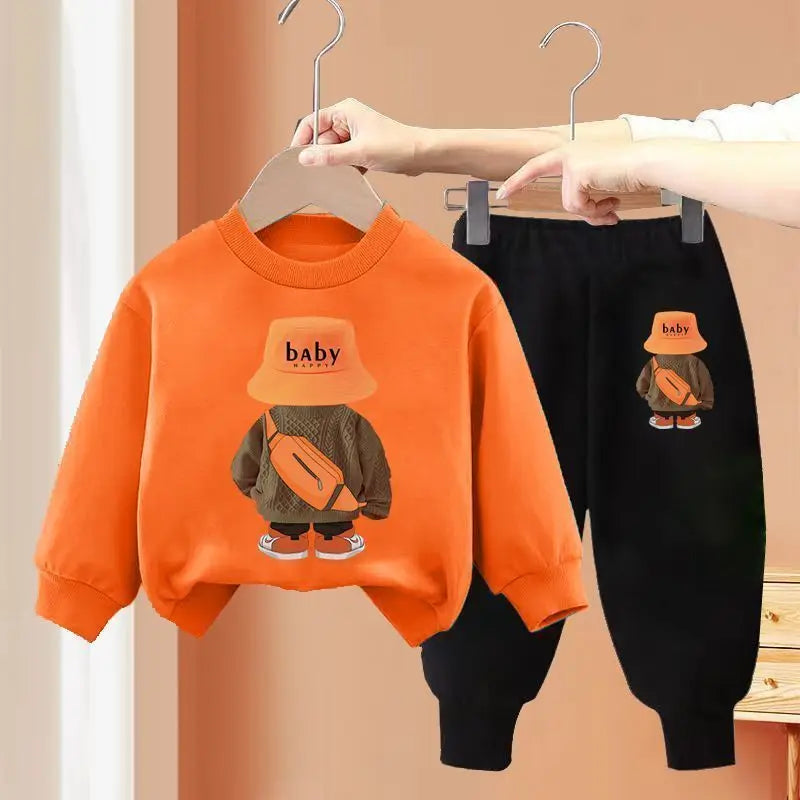 Orange sweatshirt and black pants with cartoon design on hangers against a beige background