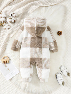Plaid baby romper on a soft white surface with decorative elements.