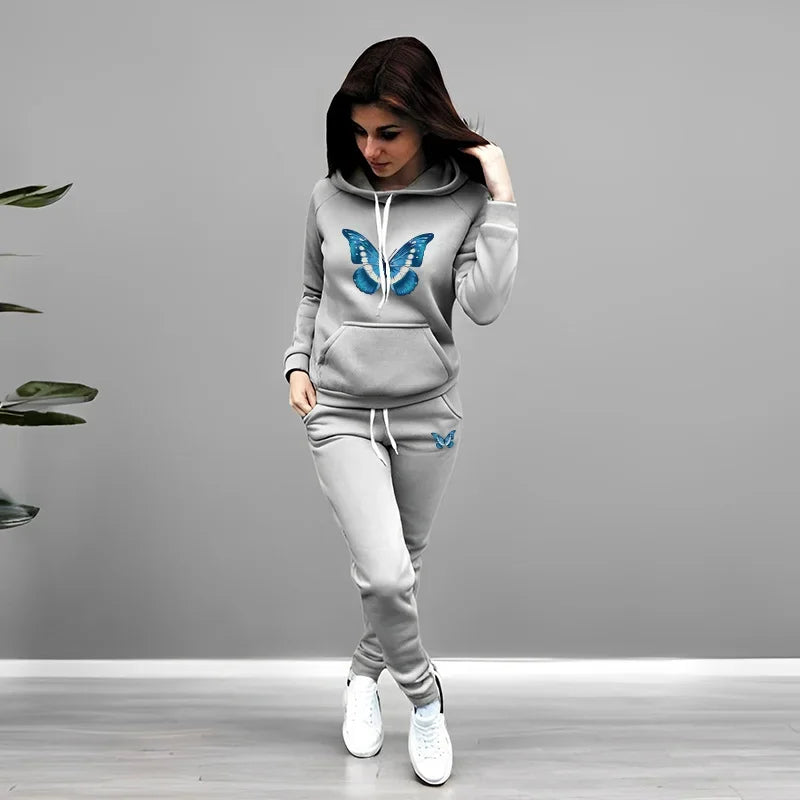 Woman wearing a gray tracksuit with butterfly designs on a plain background