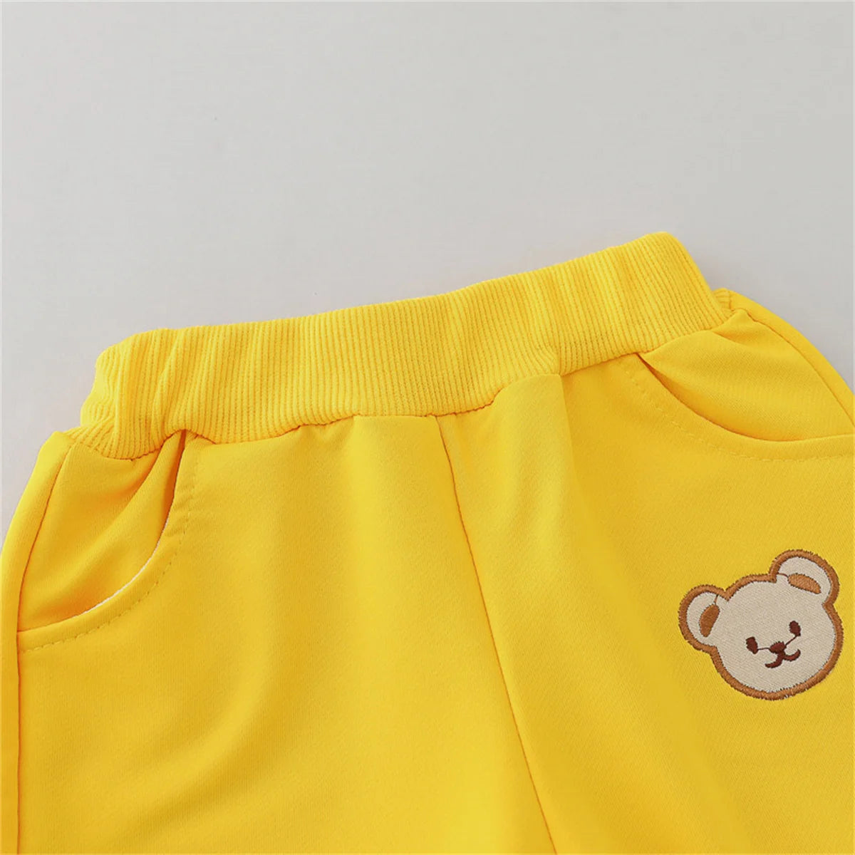 Yellow pants with a teddy bear patch on a gray background