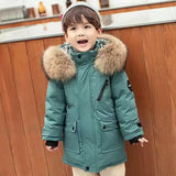 Child wearing a teal winter coat with a fur-lined hood in a kitchen setting