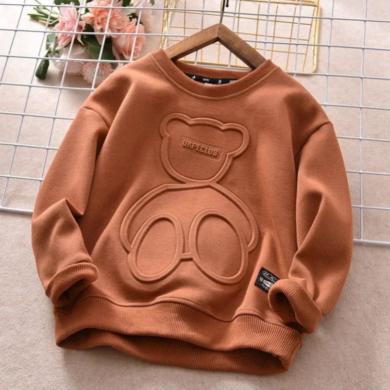 Brown sweatshirt with bear design on a hanger against a wire basket background