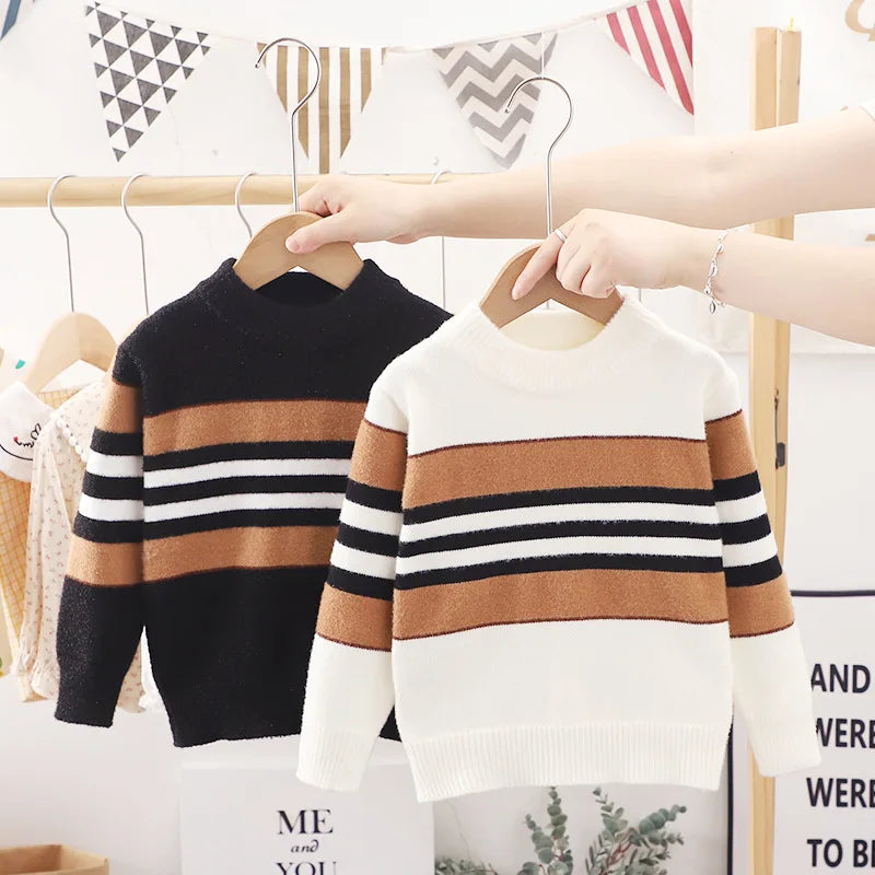 Two children's striped sweaters on hangers with a blurred background.