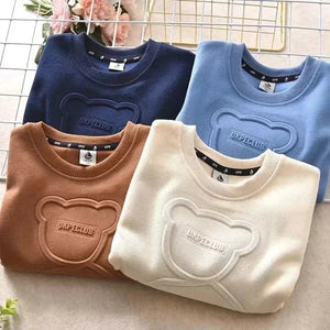 Four folded sweaters in blue, brown, and beige with a brand logo on a neutral background.