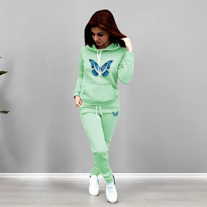 Woman wearing a light green tracksuit with butterfly designs on a gray background