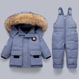 Children's blue winter coat with fur-lined hood and matching snowsuit on a gray background