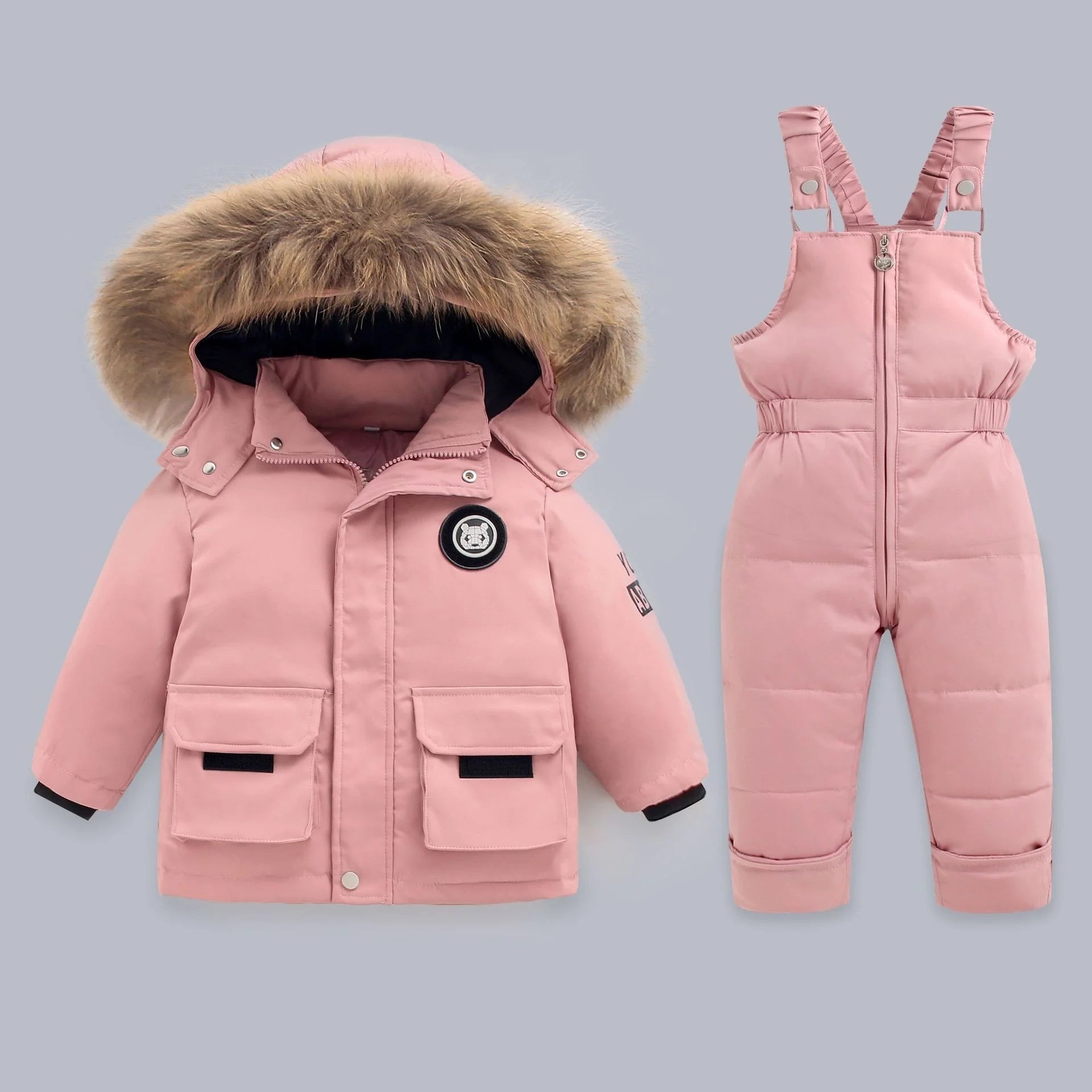 Pink winter coat with fur hood and matching snowsuit on a gray background