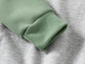 Close-up of green sweater sleeve on gray fabric background