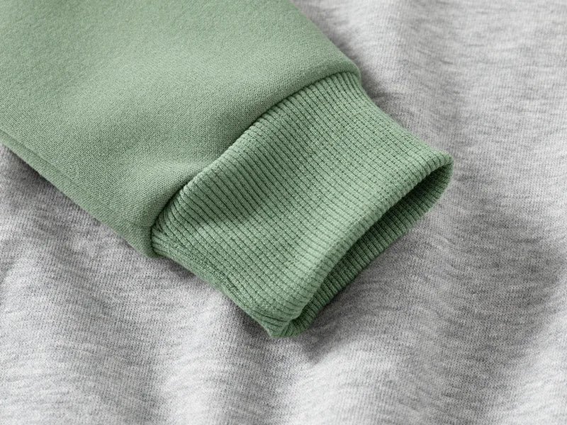 Close-up of green sweater sleeve on gray fabric background