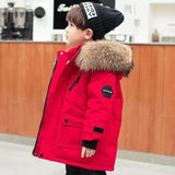 Child wearing a red winter coat with fur hood in an indoor setting