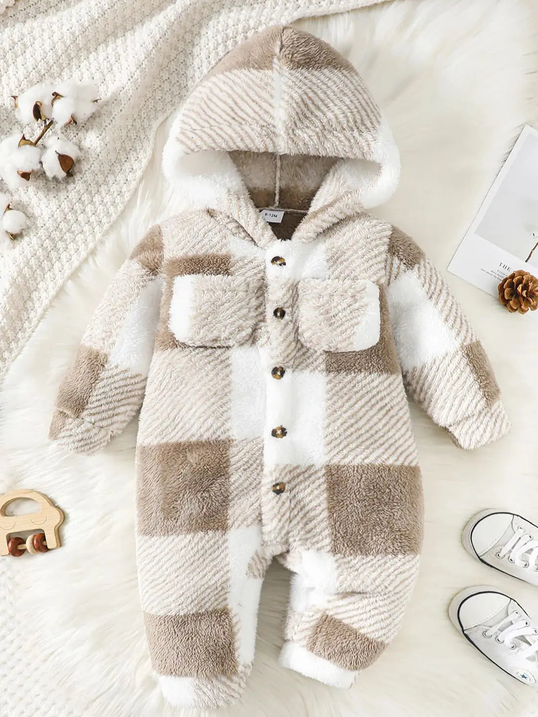 Plaid baby romper with matching hat on a soft surface