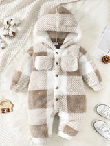 Plaid baby romper with matching hat on a soft surface
