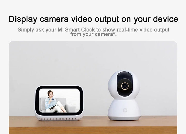 Mi Smart Clock displaying video output with a camera device on a wooden surface.