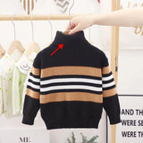 Children's striped sweater with a red arrow pointing to a small detail, hanging on a rack.