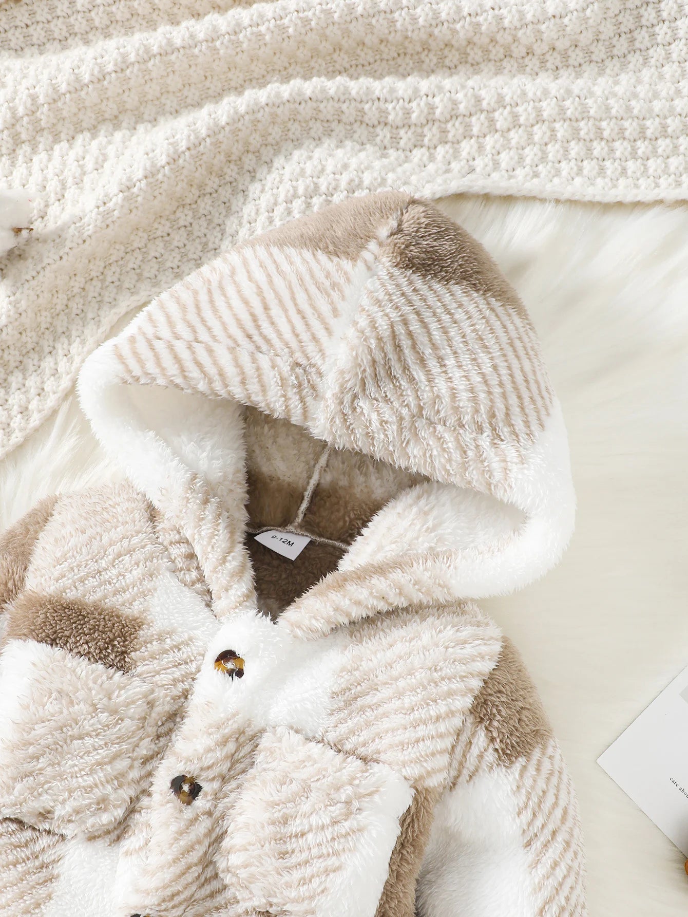 Close-up of a textured beige and brown garment with a tag on a light background
