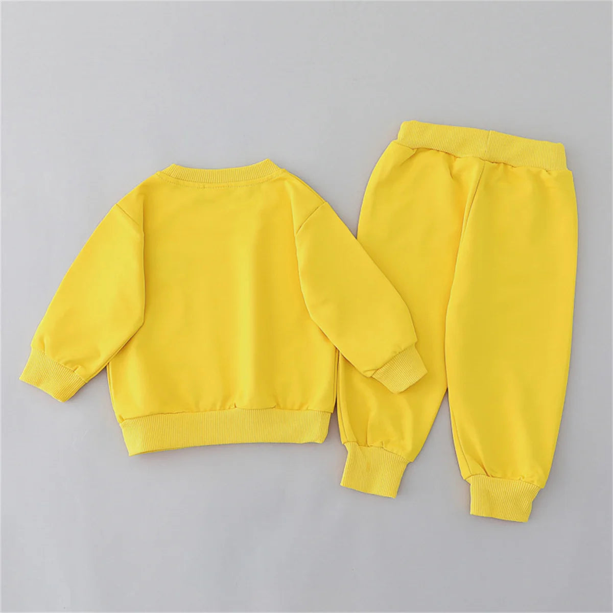 Yellow children's sweatshirt and pants set on a gray background
