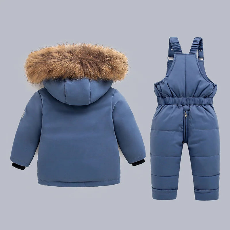 Blue children's winter coat with fur hood and matching snowsuit on a gray background